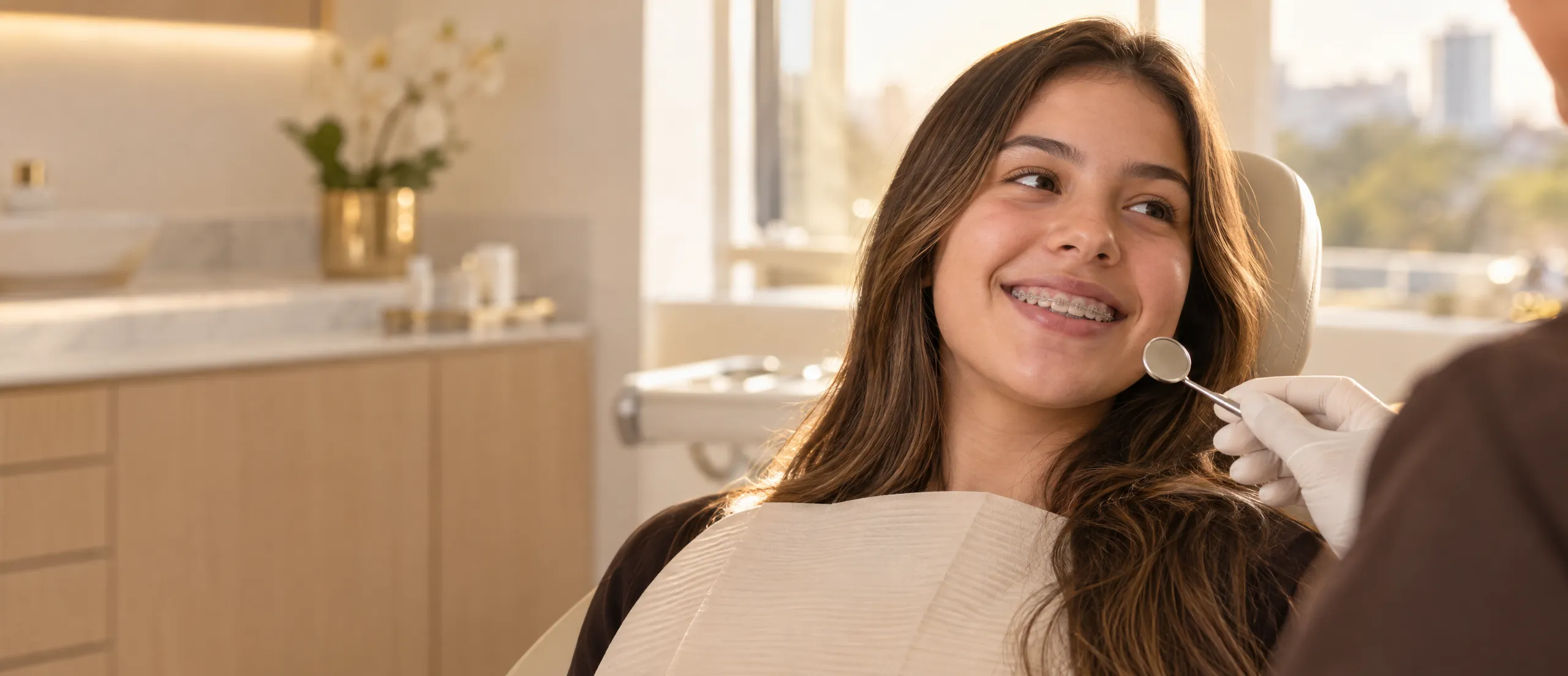 Adolescente sorrindo na cadeira odontológica com aparelho fixo nos dentes